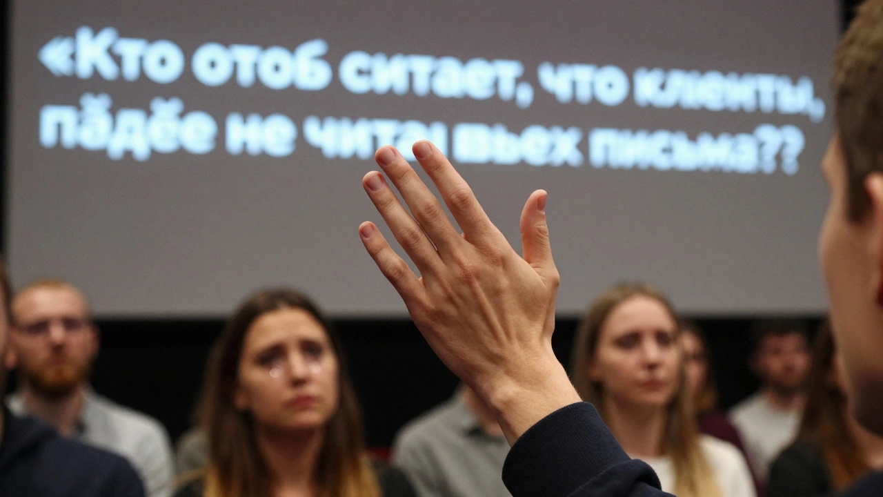 Рука человека, поднимающаяся в ответ на вопрос на конференции, зрители в размытом фоне.